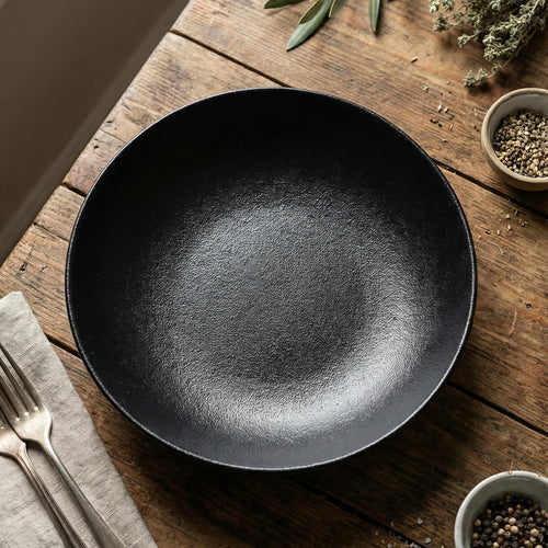 Assiette creuse en porcelaine RAK noire sur une table